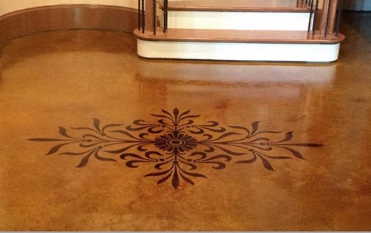 sophisticated floral stencil in dark brown in tan stained concrete overlay in a entry to a home 