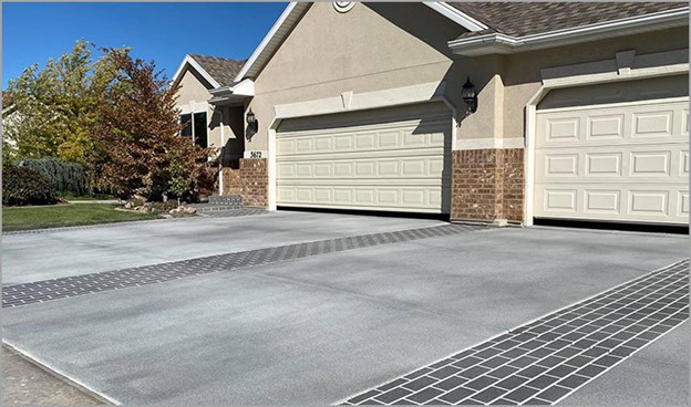 large driveway with gray concrete coating and stenciled brick 