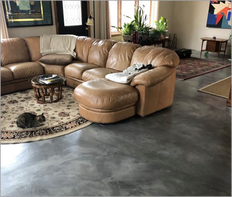 Gray polished concrete floor in a home with a couch and area rugs 